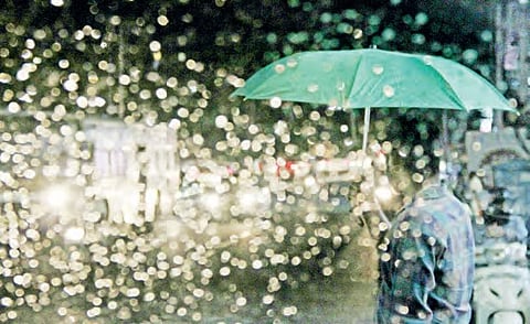 A man shields himself with an umbrella during heavy rain at Banjara Hills, in Hyderabad  on Sunday | r satish babu