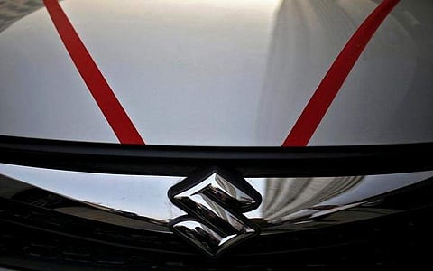 The logo of Maruti Suzuki India Limited is seen on car parked outside a showroom. (File | Reuters)