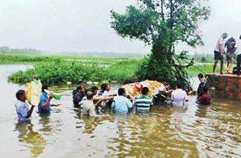 Villagers walk across a stream carrying a body near Ankola of Uttara Kannada district (File | EPS)