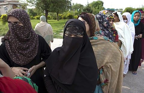 People wait in queue at a polling station to cast their votes in Islamabad, Pakistan, Wednesday, July 25, 2018. After an acrimonious campaign, polls opened in Pakistan on Wednesday to elect the country's third straight civilian election, a first for this 