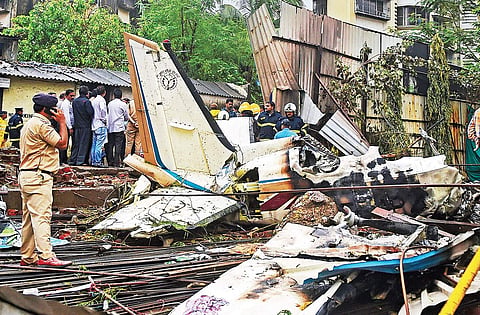 Rescue personnel stand near the debris of the chartered plane that crashed in Ghatkopar, Mumbai, killing five persons. | PTI File Photo