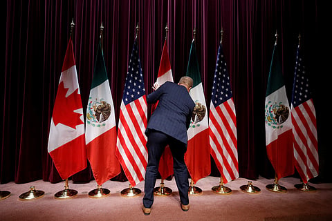 A staff member moves flags at the close of the third round of NAFTA talks involving the United States, Mexico and Canada in Ottawa, Ontario, Canada. (Photo | Reuters)