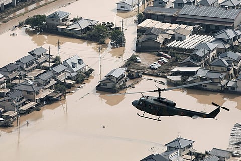 A helicopter flies over a flooded housing area in Kurashiki, Okayama prefecture, western Japan Monday, July 9, 2018. People prepared for risky search and cleanup efforts in southwestern Japan on Monday, where several days of heavy rainfall had set off flo