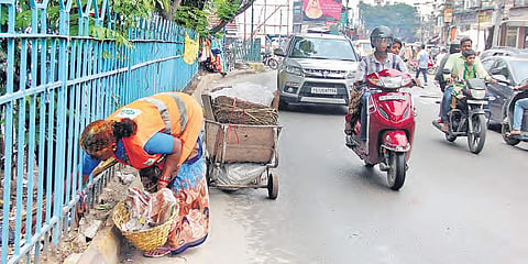 A GHMC worker collects garbage from the road while vehicles whizz past her, in Old City on Friday | Sathya Keerthi