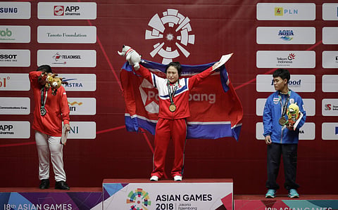 Gold medalist North Korean Ri Song Gum, center, reacts beside silver medalist Indonesia Sri Wahyuni, left, and bronze medalist Thailand's Thunya Sukcharoen during presentation ceremonies at the women's 48kg weightlifting games at the 18th Asian Games in J