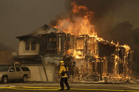 A firefighter walks near a flaming house in Santa Rosa, Calif. Nearly a year after California’s most destructive set of blazes in state history. (Photo | AP)