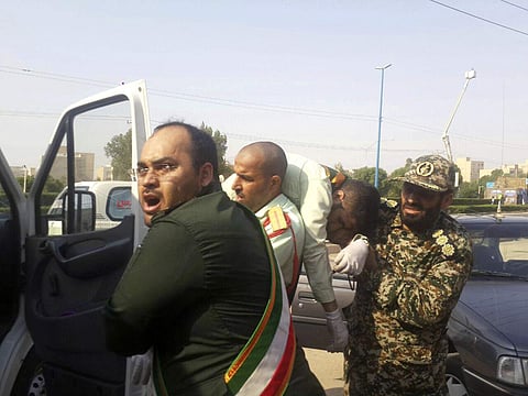 In this photo provided by the Iranian Students' News Agency, ISNA, Revolutionary Guard members carry a wounded comrade after a shooting during their parade marking the 38th anniversary of Iraq's 1980 invasion of Iran, in the southwestern city of Ahvaz, Ir