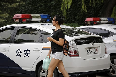 Ren Liping walks by police vehicles parked outside the police headquarters as she prepares to file a petition for her case to be re-examined in Beijing. (Photo | AP)