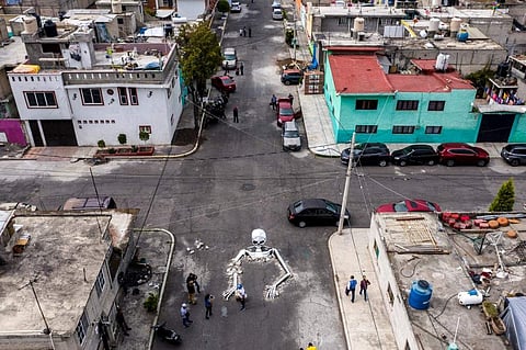 Locals look at a huge cardboard skull made by artisans in a street in the Tlahuac neighborhood, in Mexico City. (Photo | AFP)