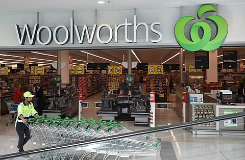 A worker pushes shopping trollys at a Woolworths store in Sydney on August 25, 2016. Australian supermarket giant Woolworths on August 25 reported a large annual net loss of AUD 1.23 billion (USD 940 million), its first since listing more than two decades