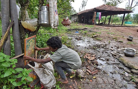 A boy places a portrait of Goddess Chamundeshwari in front of his  damaged house in Konasahalli in Hunsur. (Photo | Udayshankar S, EPS)