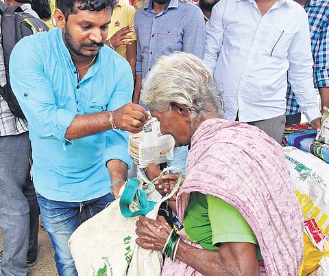A Mana Peddapuram  member distributing rice to an eldery lady | Express