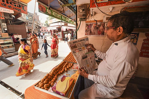 A shopkeeper near the disputed land reads newspaper fronted with headlines on Ayodhya case verdict. (Photo | PTI)