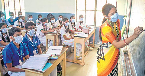A teacher and her students wear pollution masks at a Gurugram school on. (Photo | PTI)