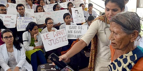 Doctors from Minto Hospital in Bengaluru stage a dharna on Tuesday, while some  help patients visiting the hospital.(Photo | Nagaraga Gadekal, EPS)