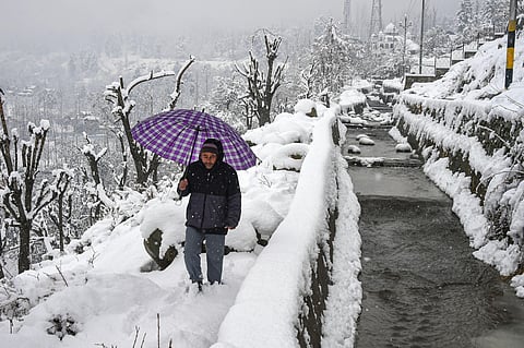 A man walks on a snow-covered path to climb up hill during snowfall on the outskirts of Srinagar Friday Dec. 13 2019. (Photo | PTI)