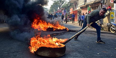 A demonstrator burns tyres on National Highway 17 during a protest rally against CAB at Boko in Kamrup district of Assam. (Photo | PTI)