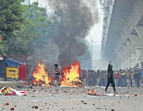 Protesters react after teargas shells were fired by the police during a demonstration against the new citizenship law in the national capital | Parveen Negi