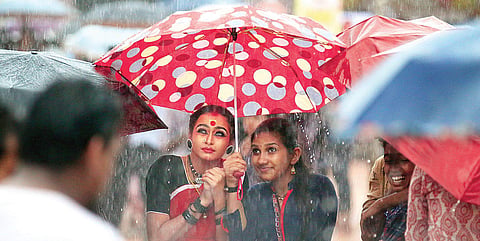 Parvathi Krishna (left) of GHSS Kayyur, and her friend Anjima Aravind, take cover under an umbrella as heavy rain lashes the main venue during the prize distribution ceremony of the State School Arts Festival in Kanhangad on Sunday. Parvathi, daughter of 