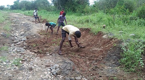 Tribal students and youth digging a path to reach Arakadavu and Moonukuttai near Karamadai in Coimbatore. (Photo | EPS)