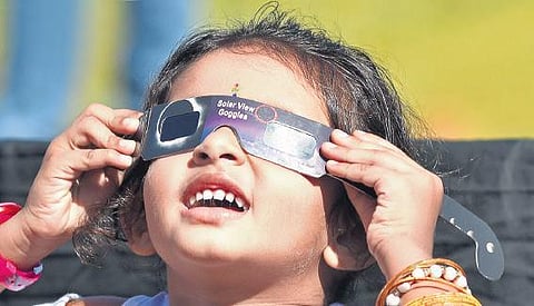 A child watches the annular solar eclipse using special goggles. B P Deepu