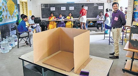 Officials await voters, as voting went on in a snail-paced manner in Valaiyur village near Manachanallur on Monday. (Photo | EPS/m k ashok kumar)