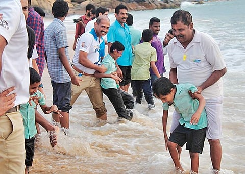 Volunteers along with children who are  visually impaired enjoying the waves at Kovalam beach  | EXPRESS