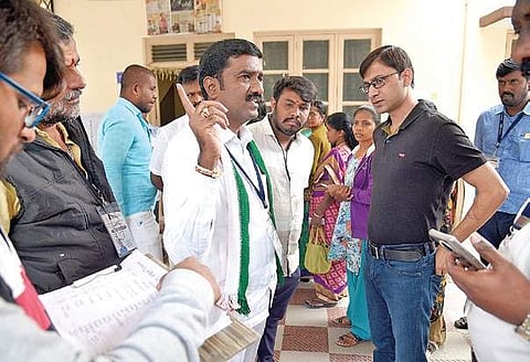 An observer interacts with Congress’ M Shivaraju about a snag in  the EVM, at a polling booth in Mahalakshmi Layout | nagaraja Gadekal