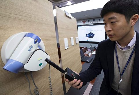 A police official testing a detector in front of a hidden mini-camera installed in a hair-dryer holder as South Korean police talk to the media about the latest spycam-related crime at the Korean National Police Agency in Seoul. (Photo| AFP)