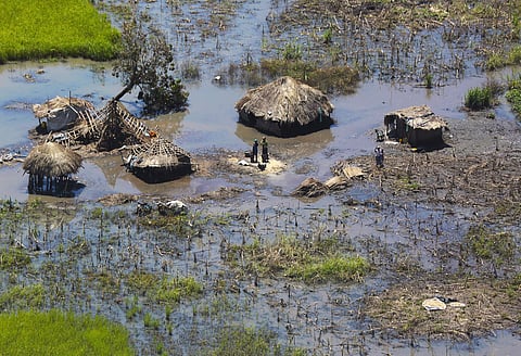 A  family stand outside their submerged huts near Beira, Mozambique. (Photo | AP)