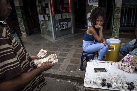A customer counts Bolivar banknotes before purchasing coffee and sugar in the Petare slum of Caracas. (Photo | Bloomberg)
