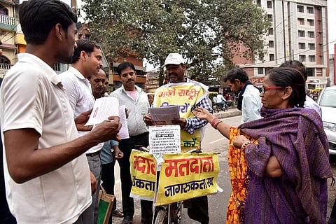 In this file taken on March 26, 2019, Lal Mani Das is seen handing out voting information pamphlets to prospective voters  in Patna. (Photo | AFP)