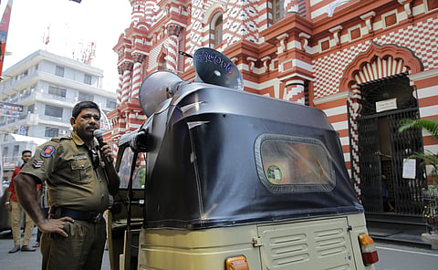 A Sri Lankan police officer announces security warnings urging people to be cautious over abandoned vehicles and parcels in a street outside a mosque in Colombo (Photo|AP)