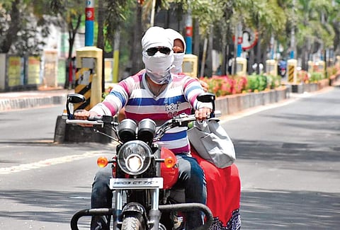 A motorist and pillion rider cover their faces to escape from heat in Tirupati on Sunday | Madhav K