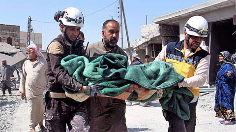 This photo provided by the Syrian Civil Defense group known as the White Helmets, shows members of the Syrian Civil Defense workers carrying a victim after a deadly airstrike hit a market killing several people in the village of Ras el-Ain, in the northwe