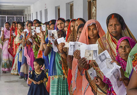Women show their voter identity cards as they stand in a queue at a polling station during the 5th phase of Lok Sabha polls in Chhapra district of Bihar. (Photo | PTI)