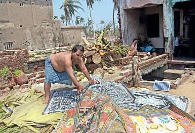 An artist drying damaged pattachitra paintings in Raghurajpur village on Monday I BISWANATH SWAIN