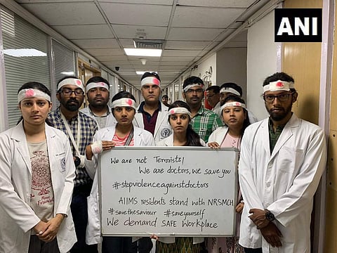 Resident doctors at the AIIMS and Safdarjung Hospital worked with bandages on their heads in a symbolic protest on Thursday and called for the suspension of all non-emergency services. (Photo | ANI)