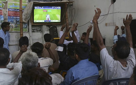 People react while watching cricket World Cup match between Pakistan and India, at a tea-stall in Karachi, Pakistan. (Photo | AP)