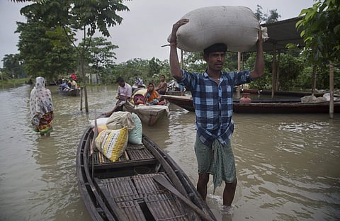 A flood affected villager carries food grains on his head in Burha Burhi village, east of Gauhati in Assam (Photo | AP)