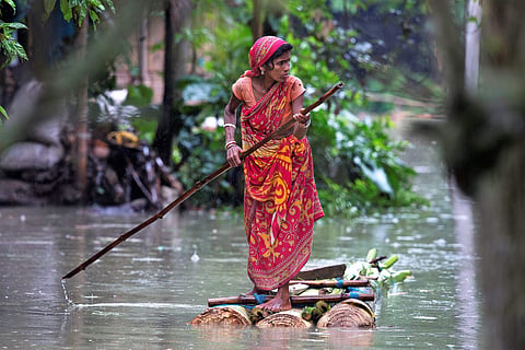 A woman rows a makeshift banana raft through flood waters in Burgaon, east of Gauhati, Assam. (Photo | AP)