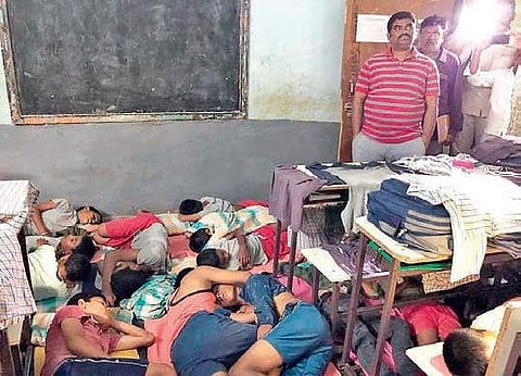 Collector G Veerapandian expresses disappointment over students sleeping on the floor inside the classrooms without bedsheets at the AP Tribal Welfare Gurukul Boys’ School in Panyam on Monday night. (Photo | EPS)