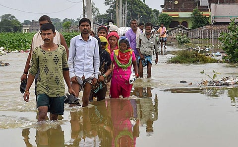 Sitamarhi residents wade across a flooded street ( Photo | PTI)
