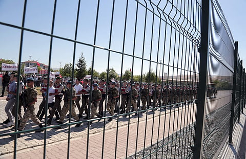 In this Aug. 1, 2017 file photo, paramilitary police and members of the special forces escort suspects of a failed coup in 2016, among them former Air Force commander Akin Ozturk, outside the courthouse at the start of a trial, in Ankara, Turkey.  (File p