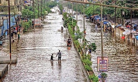 People walk on waterlogged railway tracks owing to heavy rains at Tilak Nagar Station in Mumbai on Tuesday  | PTI