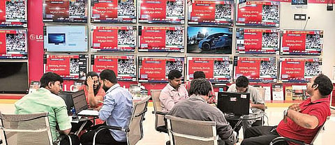Employees and customers at an electronics outlet in Hyderabad keep an eye on live telecast of Budget presentation in the Parliament even as they conduct business, on Friday | S Senbagapandiyan