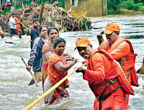 NDRF personnel rescuing flood-hit people at Ranni Kurumbanmuzhi causeway.  | (Shaji Vettipuram | EPS)