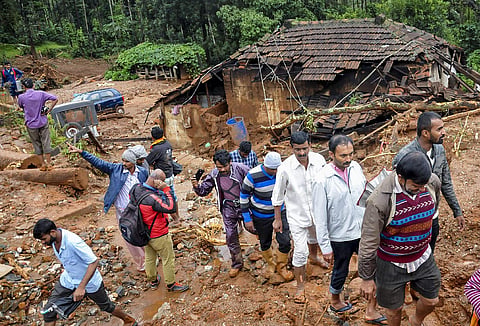 Residents pass by a partially collapsed house following a landslide due to heavy rainfall in the flood hit area of Chikmagalur district (File photo | PTI)
