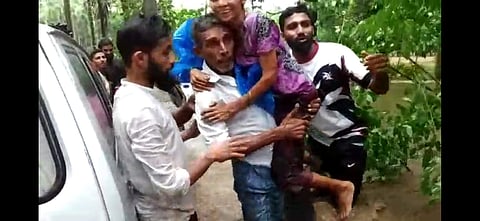 Monu carries a woman to safety in Kolambe in Dakshina Kannada. (Photo | Express)