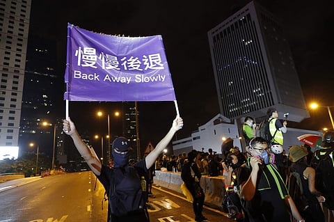 A demonstrator holds up a sign reading 'Back away slowly' to encourage other demonstrators to leave, near the Chinese Liaison Office in Hong Kong, Sunday, Aug. 18, 2019. (Photo | AP)